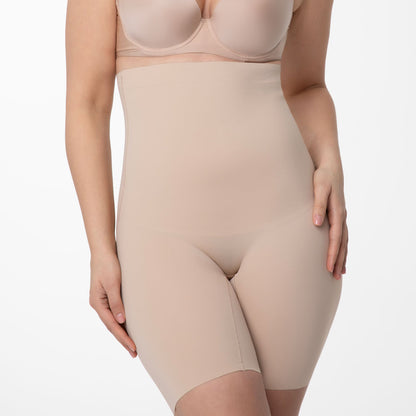 koriģējošs bodijs sievietēm, šorti ar garo malu ap vidukli, miesas. bēša krāsas uz balta fona, no priekšas tuvplāns